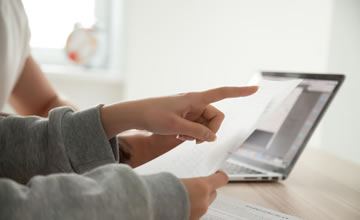 Two people pointing at a computer